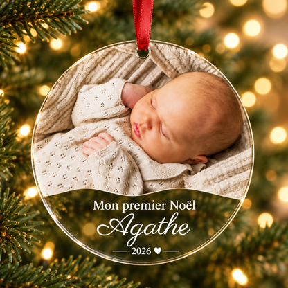 Boule de Noël personnalisée en plexiglas transparent avec photo de bébé, prénom Agathe et inscription « Mon premier Noël 2026 », suspendue dans un sapin.