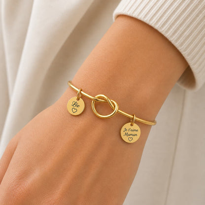 Bracelet personnalisé doré avec deux médailles gravées prénom Léo et je t’aime Maman, porté au poignet